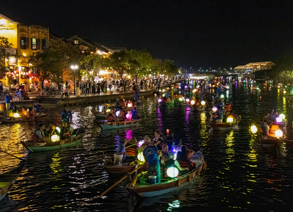 Lantern-lit boats and evening crowds along the river in Hoi An