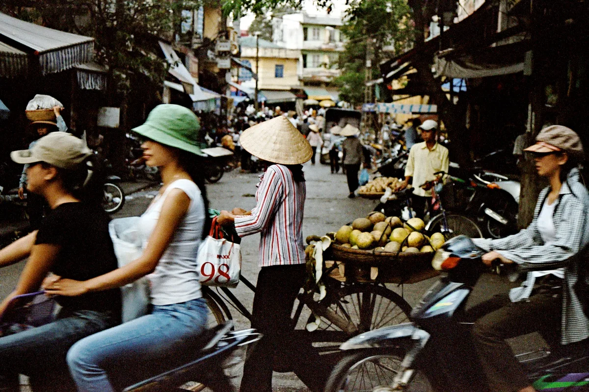 Motorbikes moving through a large Ho Chi Minh City intersection in daylight