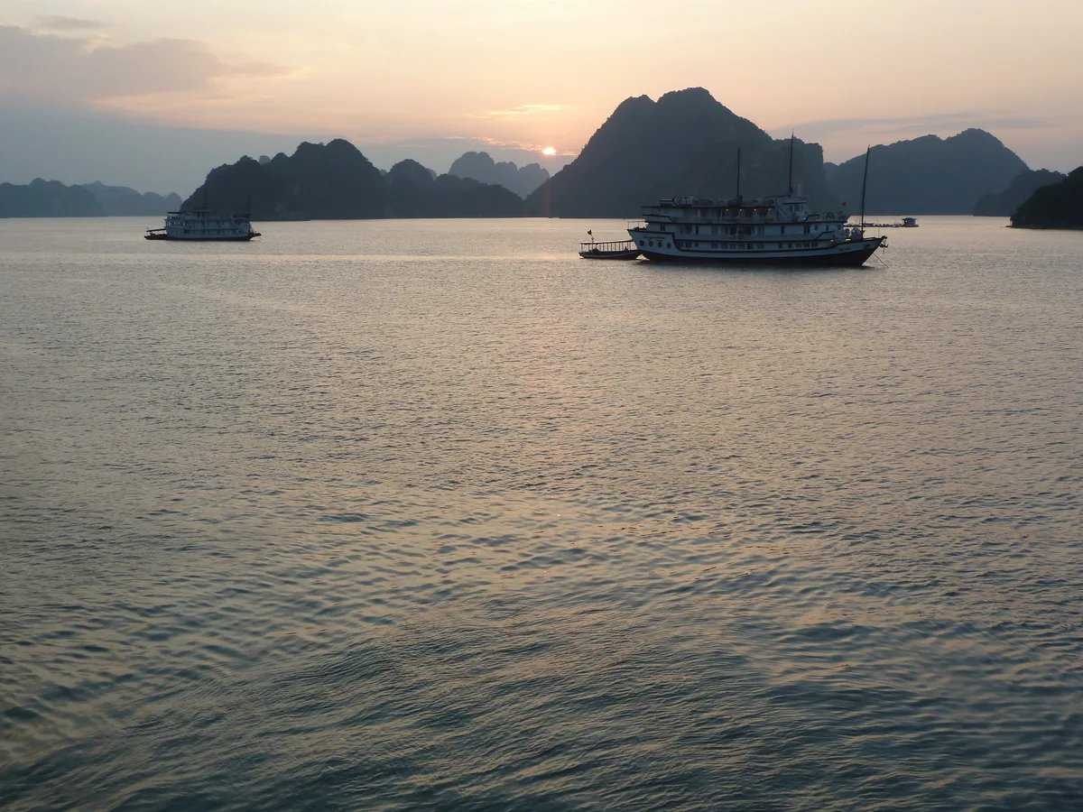 Cruise boats among limestone islands at sunset in Ha Long Bay