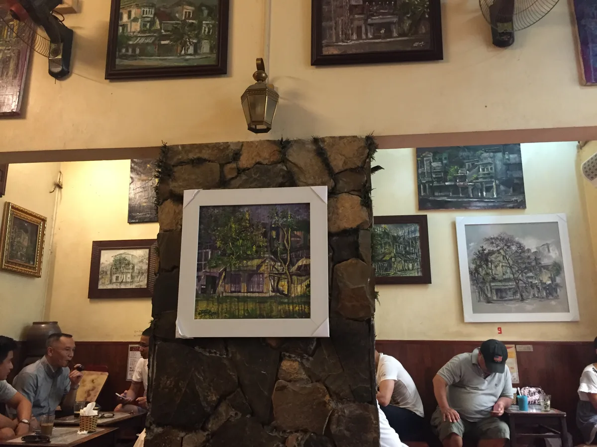Customers seated beneath local artwork inside Giang Cafe in central Hanoi