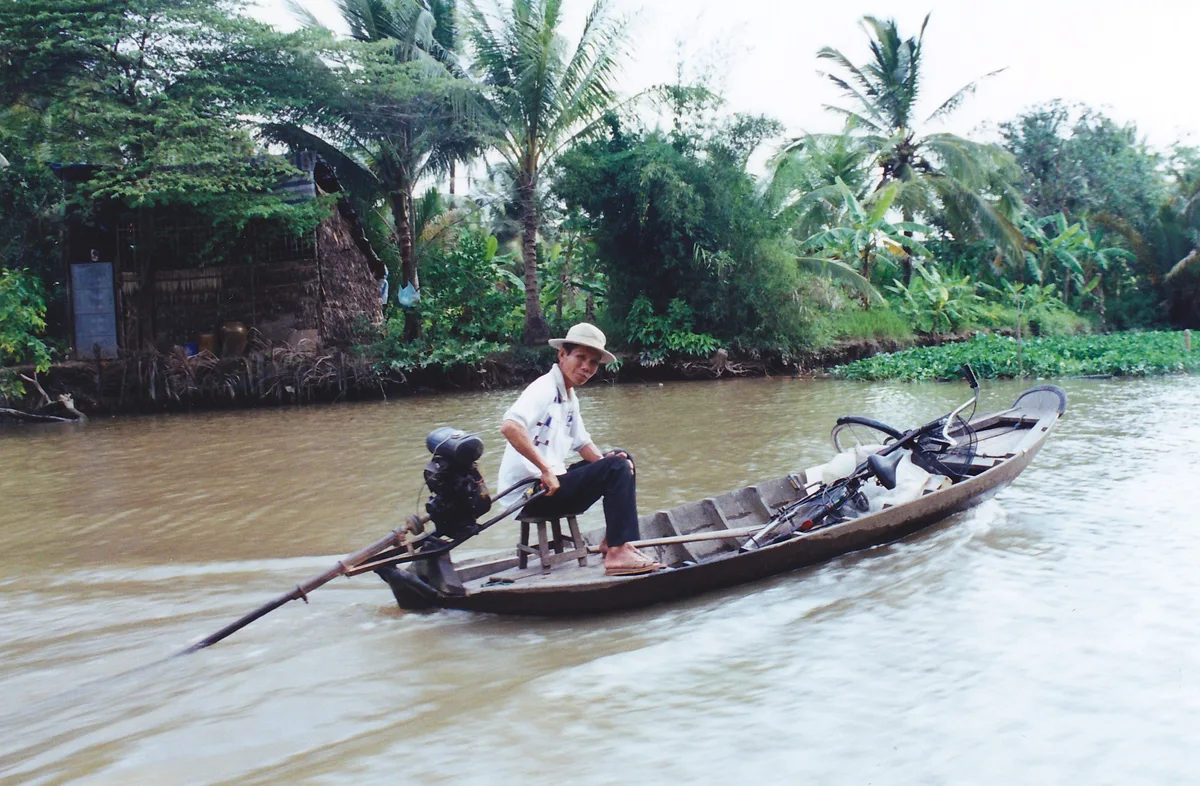 Local passenger boat traveling along a narrow Mekong Delta canal in Vietnam, contextual view for travelers planning a trip in