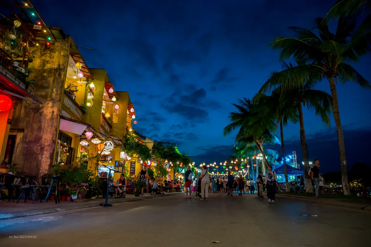 Lantern-lit restaurants and pedestrians beside the river in Hoi An Ancient Town
