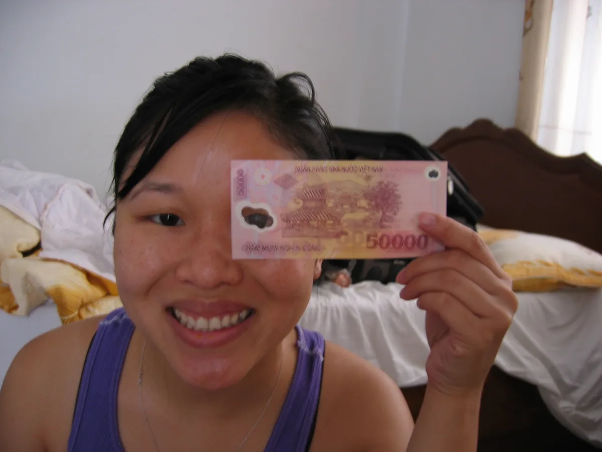 Traveler holding a fifty-thousand-dong banknote while budgeting in Vietnam, contextual view for travelers planning a trip in
