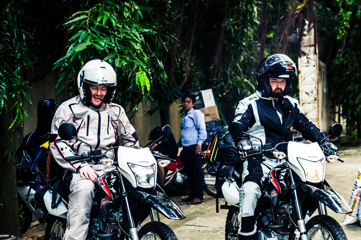 Backpackers preparing loaded motorcycles for a journey through Vietnam, contextual view for travelers planning a trip in