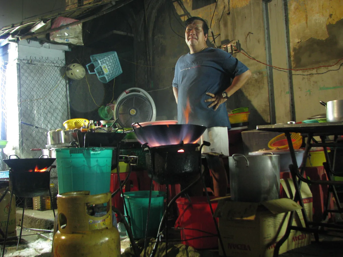 Cook preparing an affordable street-food meal at a small kitchen in Vietnam, contextual view for travelers planning a trip in